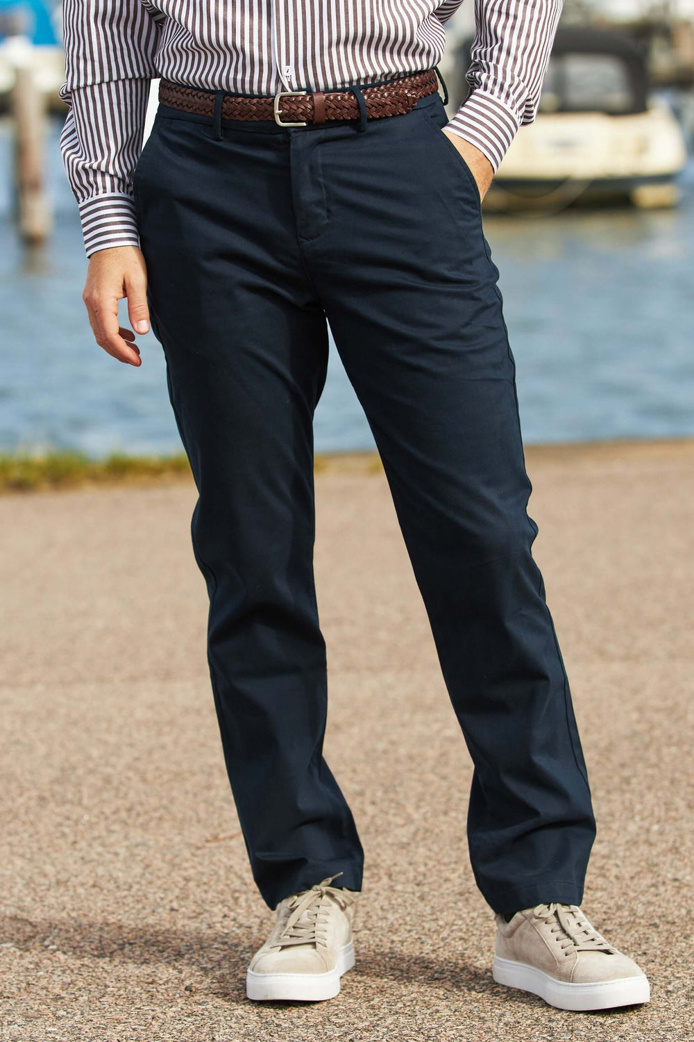 Marinblå Stretch Chinos i modern passform, bärs med skjorta och sneakers vid vattnet.
