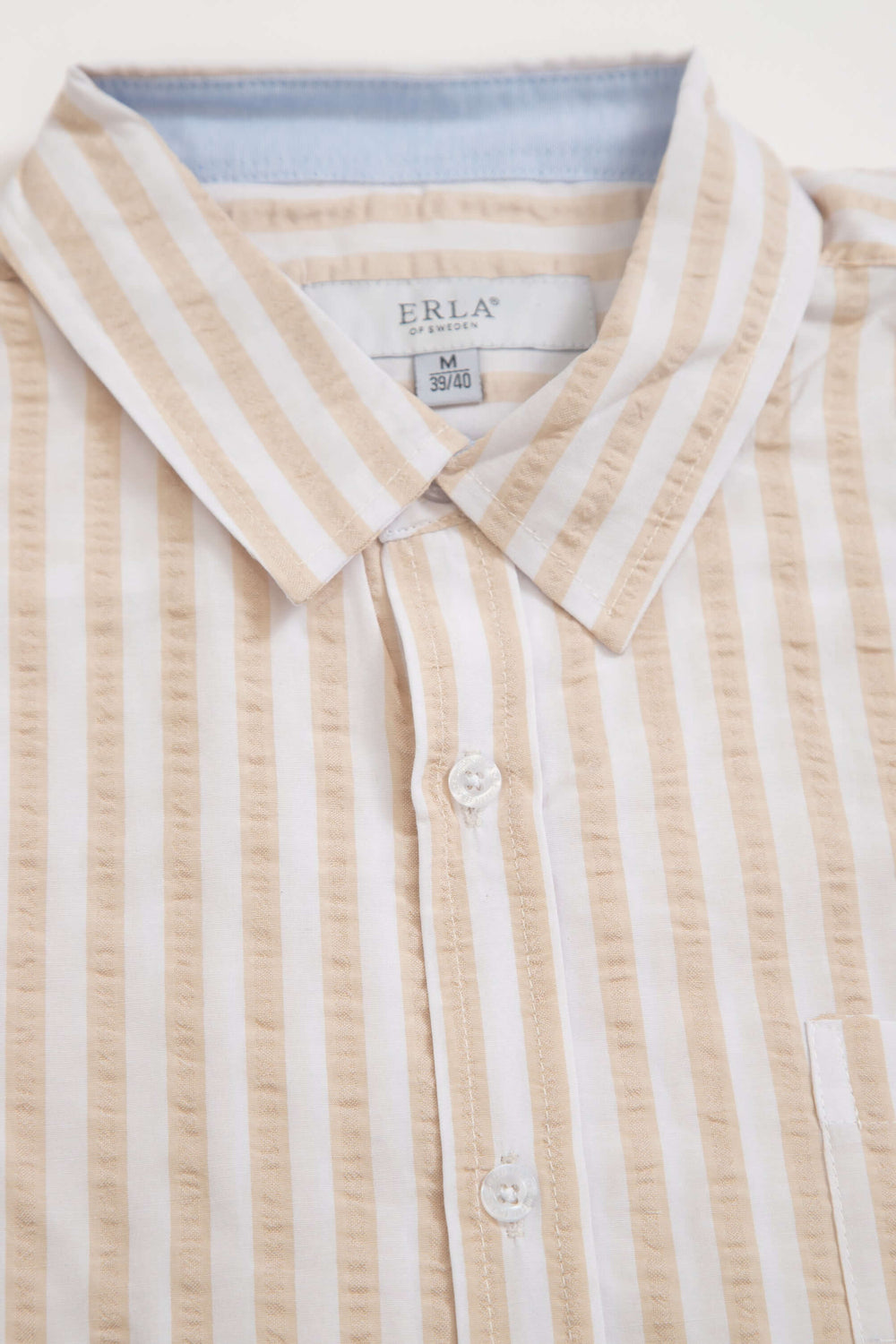 Beigerandig kortärmad seersucker-skjorta med klassiska ränder och strukturerad yta.