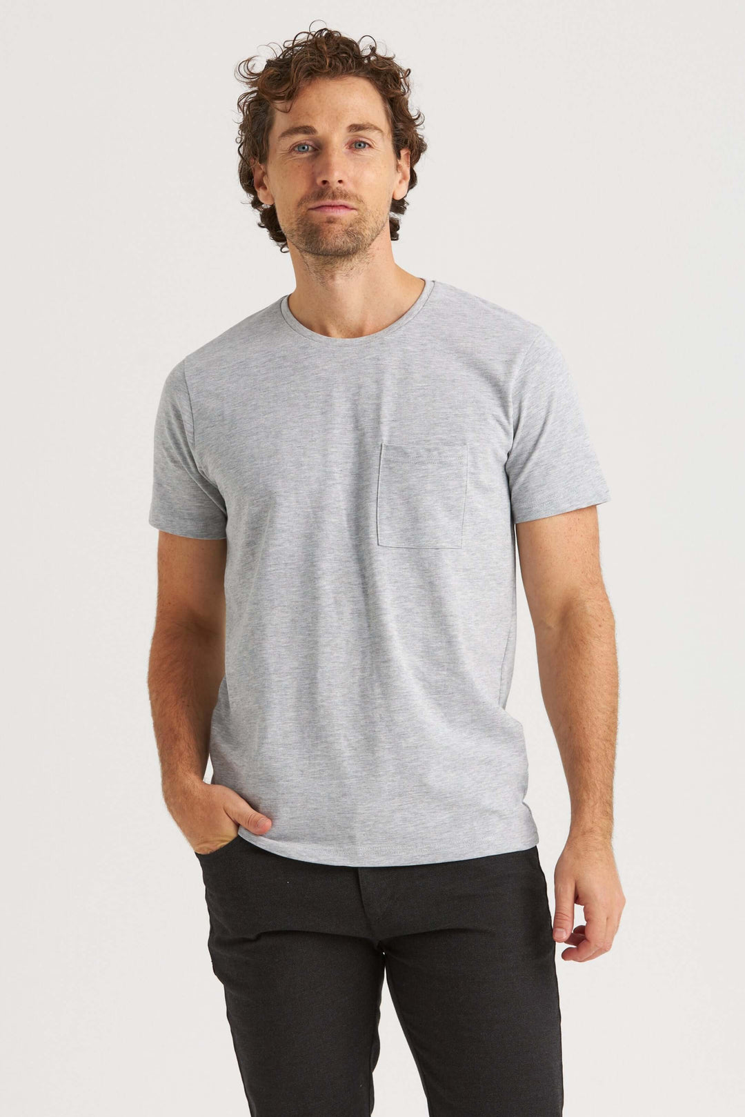 Casual grey t-shirt on a model with pocket detail, styled with black pants, suitable for everyday wear.