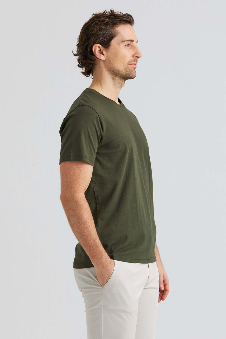 Core T-shirt Grön: Modell i profil som bär en grön T-shirt och vita byxor.