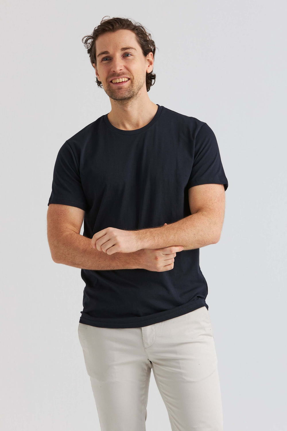 Core T-shirt Marinblå på en man med kortärmad tröja och ljusa byxor, som ler mot kameran.