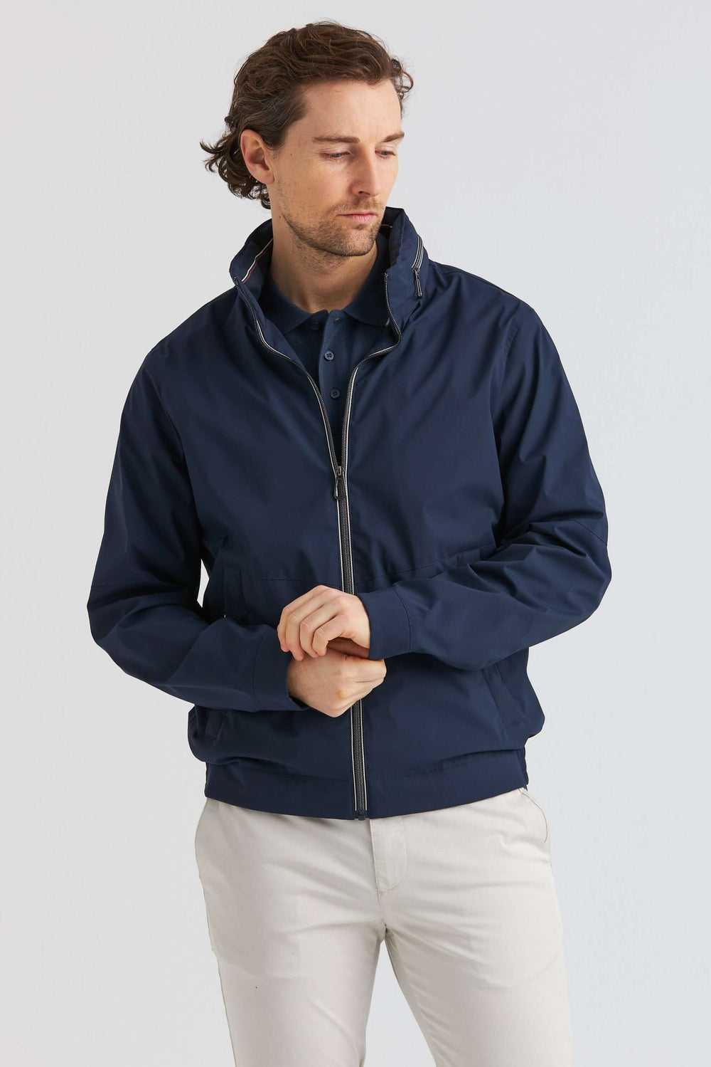Marinblå Lightweight Vårjacka på en man med vit byxa och polo, perfekt för vårens väder.