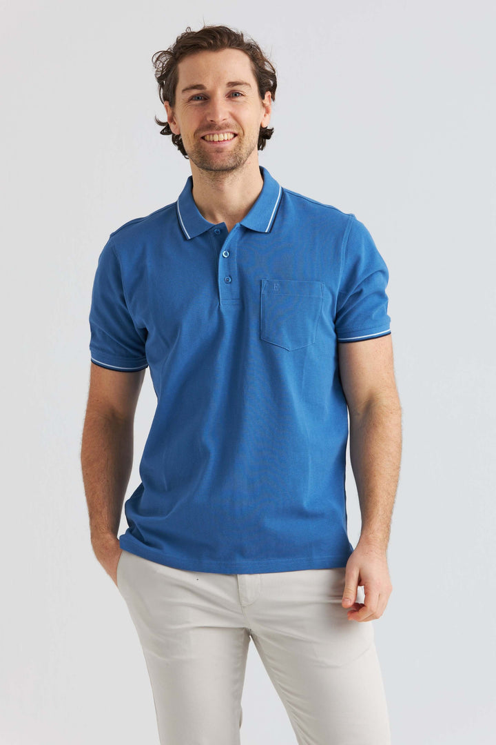 Blå Pikétröja med Kontrastdetaljer, manlig modell som poserar i en ljusblå pikétröja med kontrastdetaljer.