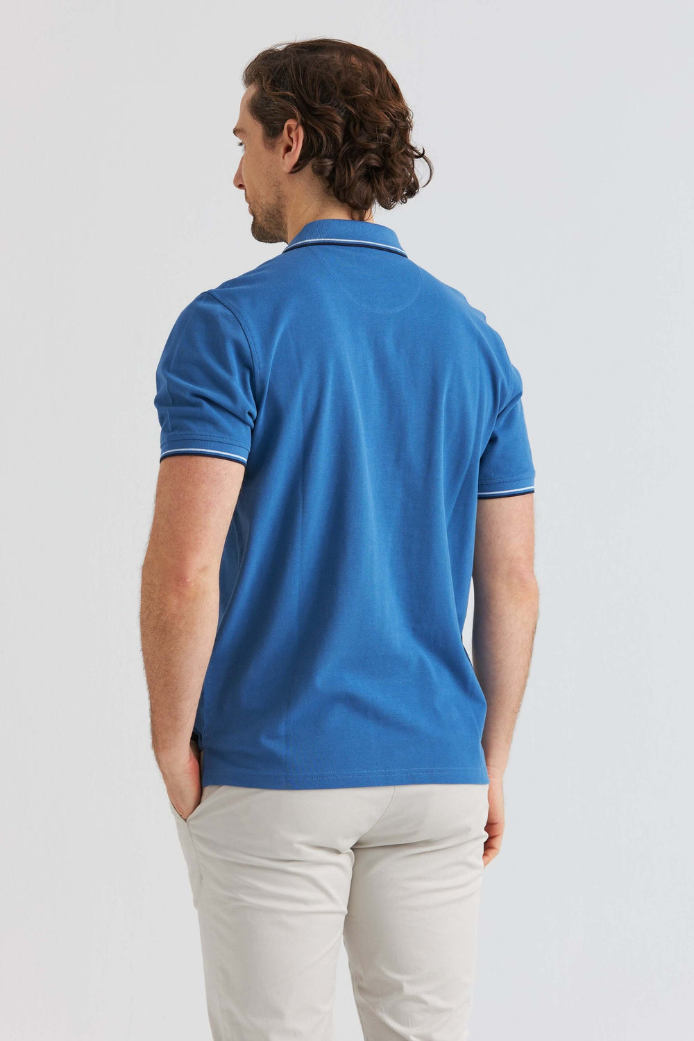 Blå Pikétröja med Kontrastdetaljer sedd bakifrån på man med ljusa byxor