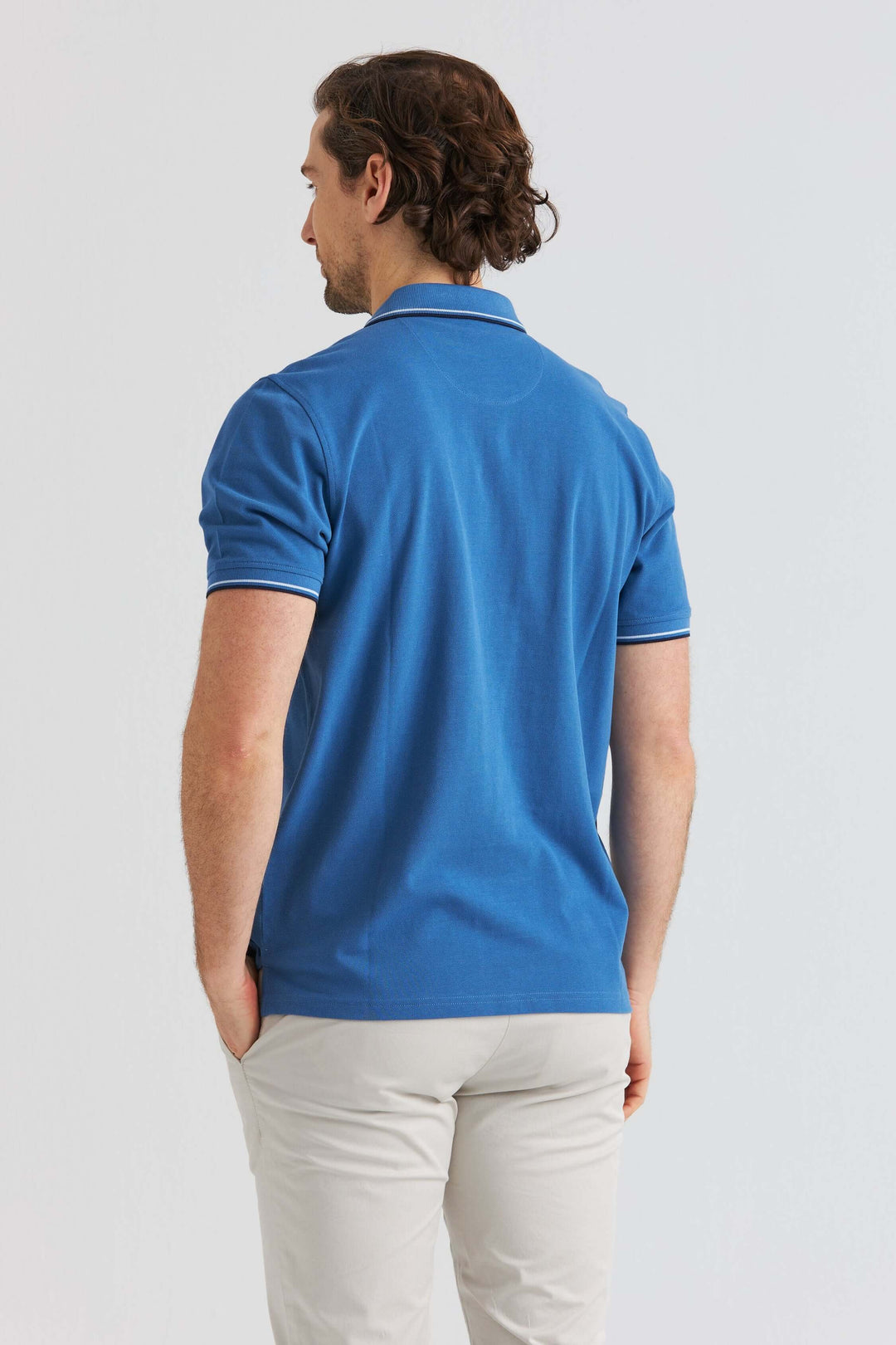 Blå Pikétröja med Kontrastdetaljer sedd bakifrån på man med ljusa byxor