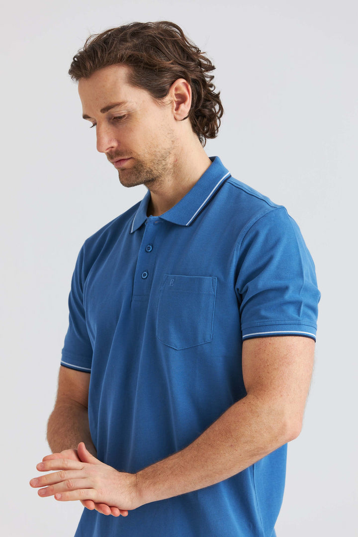 Blå Pikétröja med Kontrastdetaljer, modell bär tröjan, fokuserar på stil och detaljer.