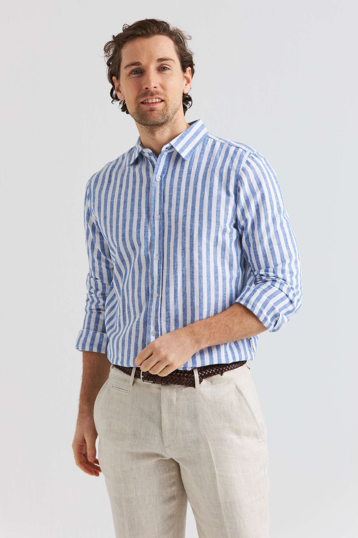 En man bär en blå randig linneskjorta i linne och bomull, perfekt för avslappnade och varma dagar.
