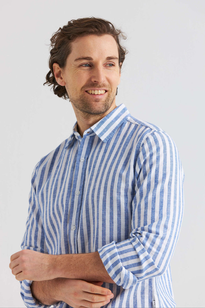 Man som bär en blå randig linneskjorta med klassisk krage, perfekt för varmare dagar.