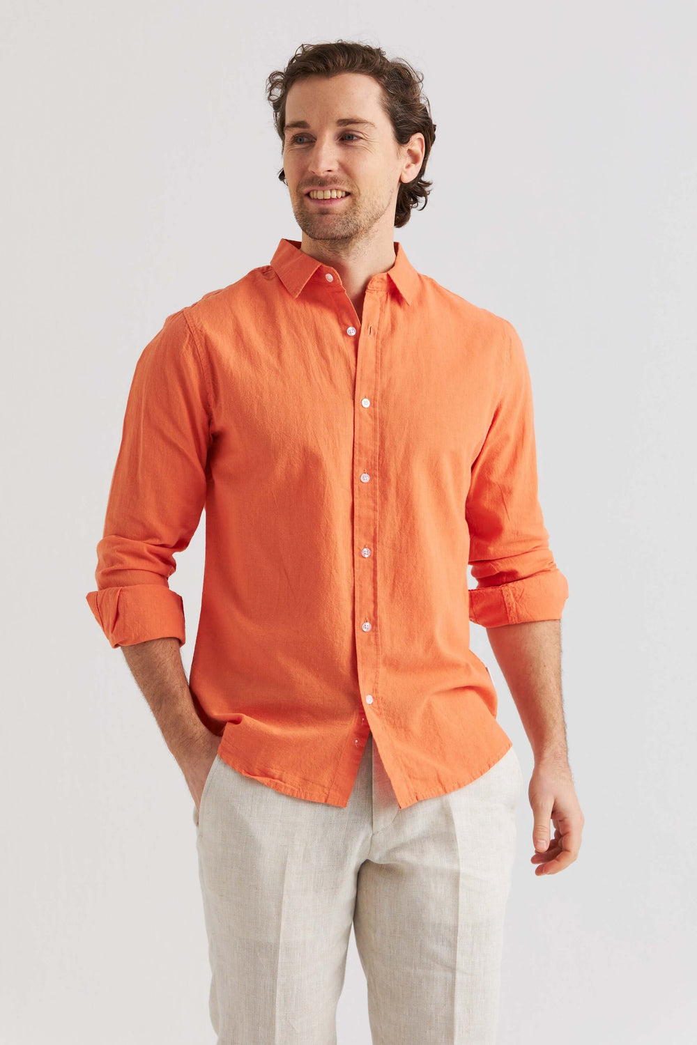 Man i linneskjorta orange med lång ärm, perfekt för vår och sommar i avslappnad stil.