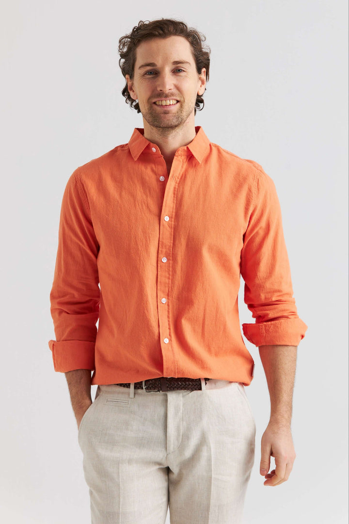 Man som bär linneskjorta orange, långärmad och stilren, perfekt för vår och sommar.
