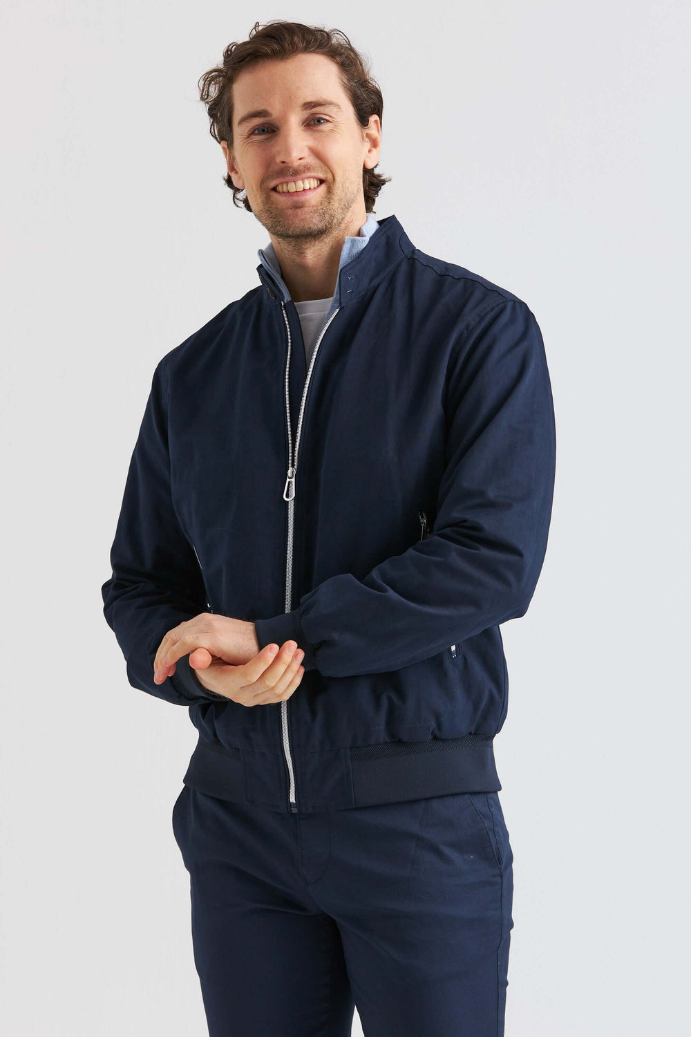 Man med ett leende i en marinblå vårjacka i bomullsblandning, perfekt för vårens mode.