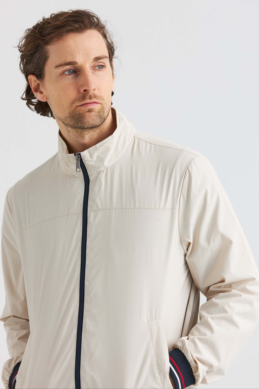 Beige Vårjacka med kontrastdetaljer bärs av man med fokus på modern design och stiliga detaljer.