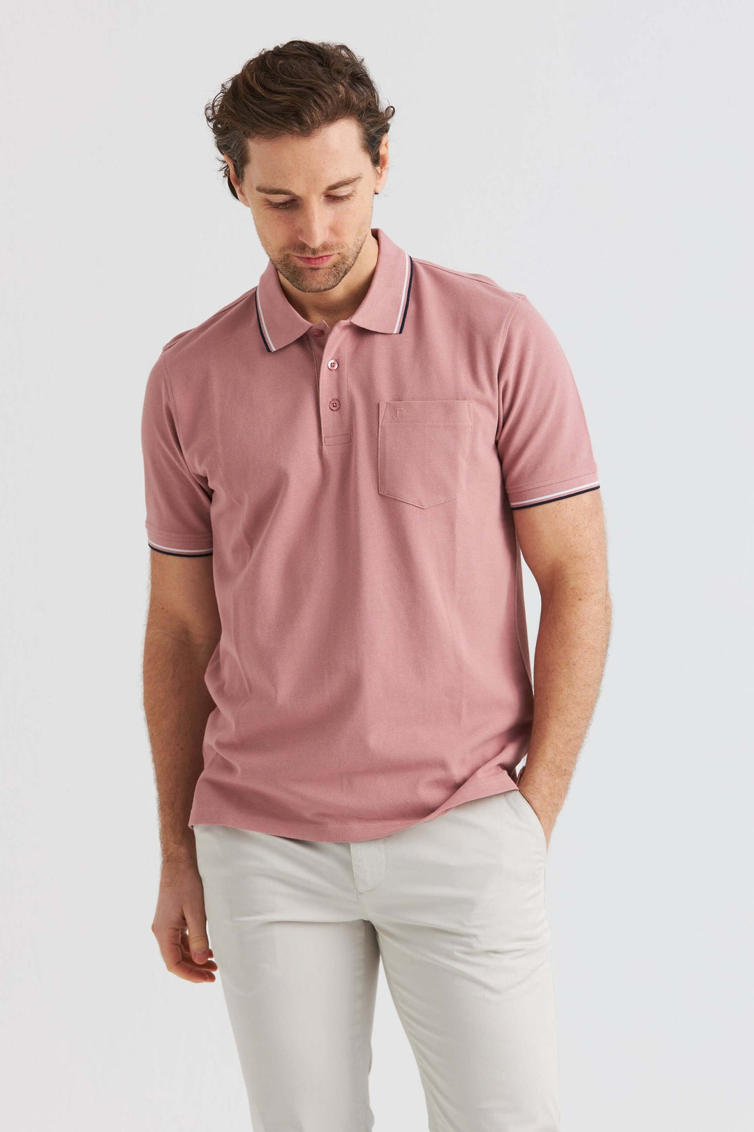 Rosa Pikétröja med Kontrastdetaljer, man bär en rosa pikétröja med kontrastdetaljer.