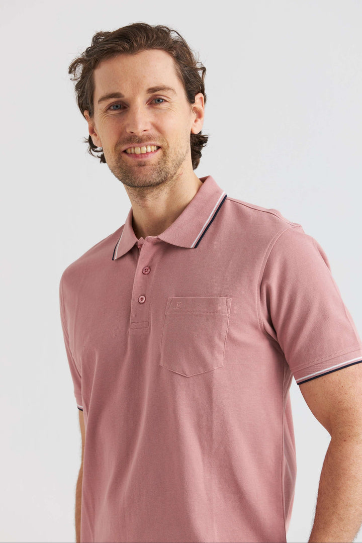 Rosa Pikétröja med Kontrastdetaljer, en man poserar i en rosa pikétröja med detaljer i kontrast.