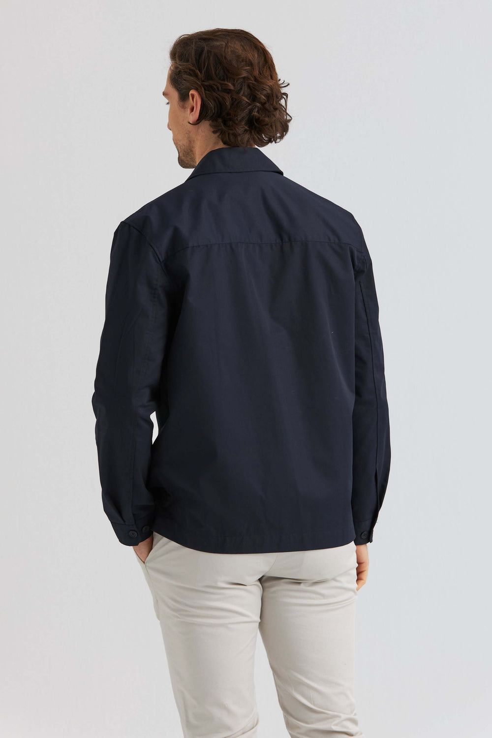 Man i marinblå City Overshirt sett bakifrån, stilren design och lätt material, perfekt för lager på coolare dagar.