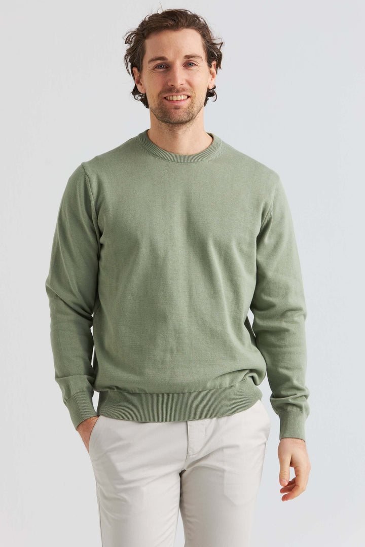 Grön bomullströja crew neck som bärs av man, kombinerad med ljusa byxor.
