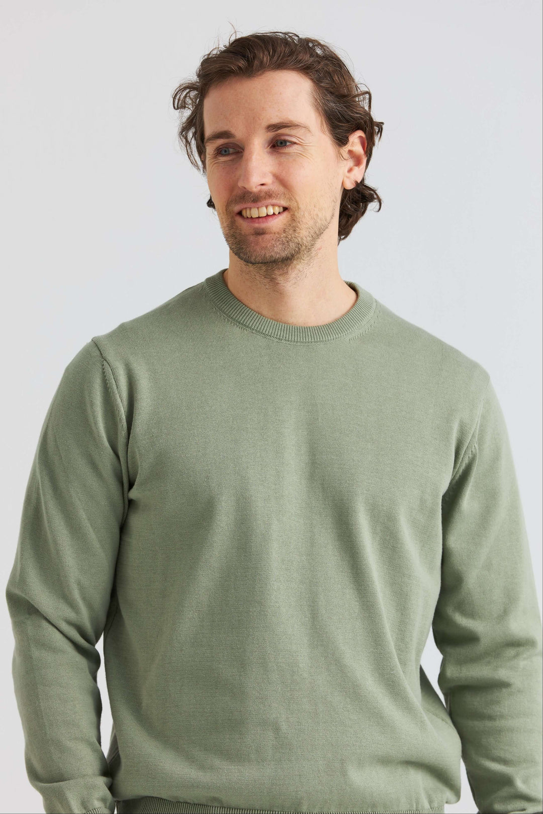 Grön bomullströja crew neck på en man som ler i en mjuk grön nyans, perfekt för avslappnade stilar.