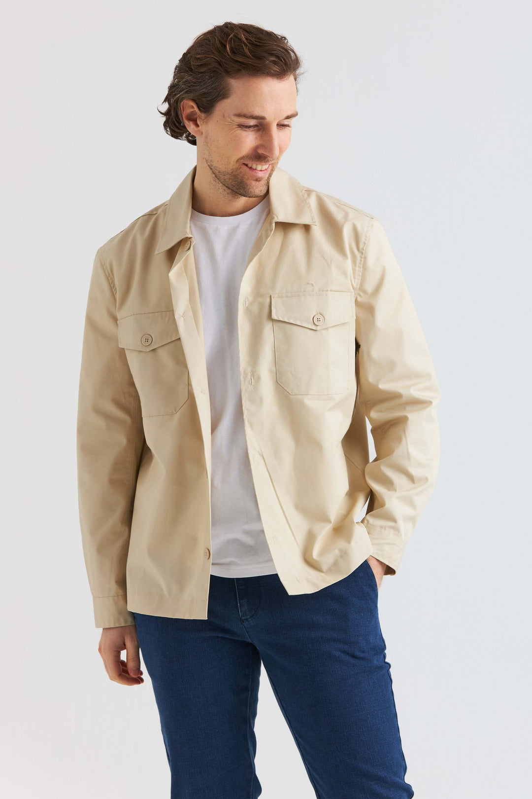 Sandfärgad City Overshirt i en avslappnad stil med bröstfickor, bärs över en t-shirt.