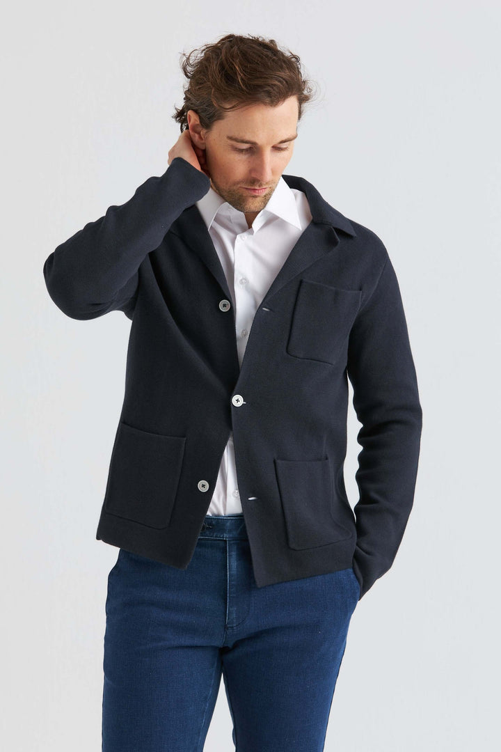 Marinblå Stickad Overshirt worn over a white shirt, featuring a stylish design and soft structure.