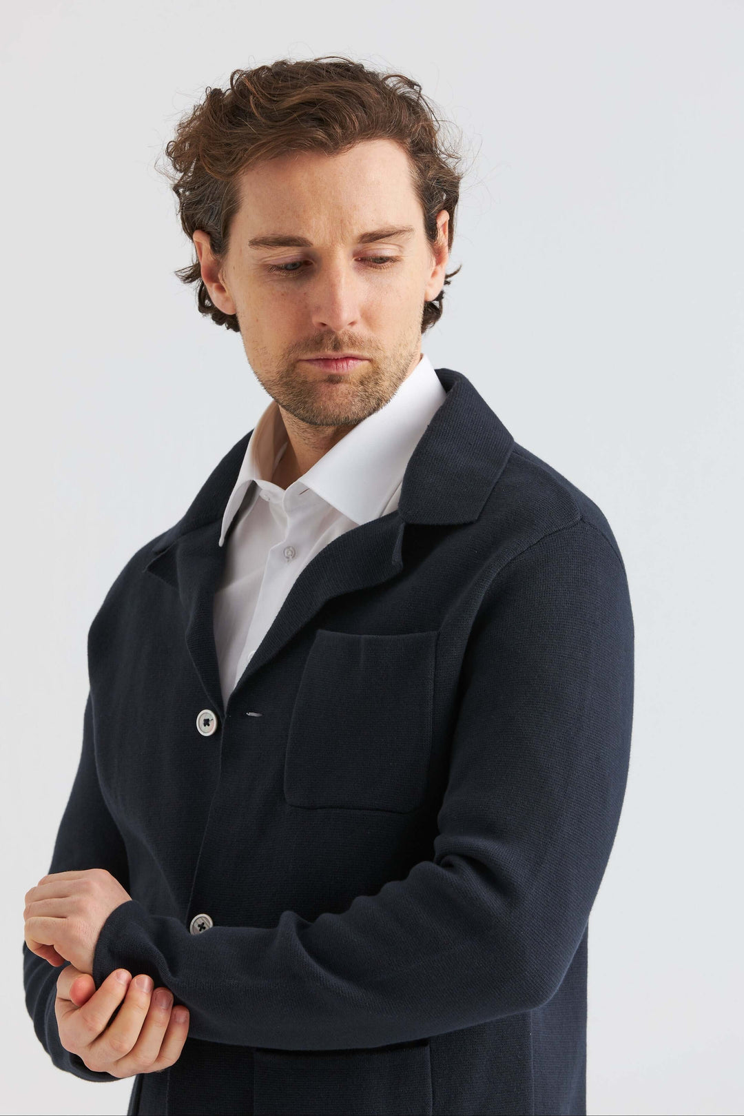 Man i marinblå stickad overshirt med vit skjorta, elegant och sofistikerad stil.