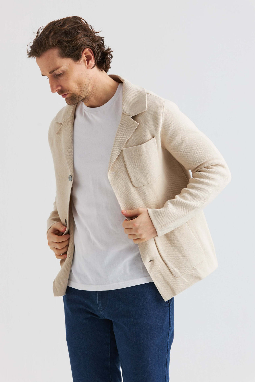Beige Stickad Overshirt bärs av man med vit t-shirt, stilren design och kavajinspirerad look.