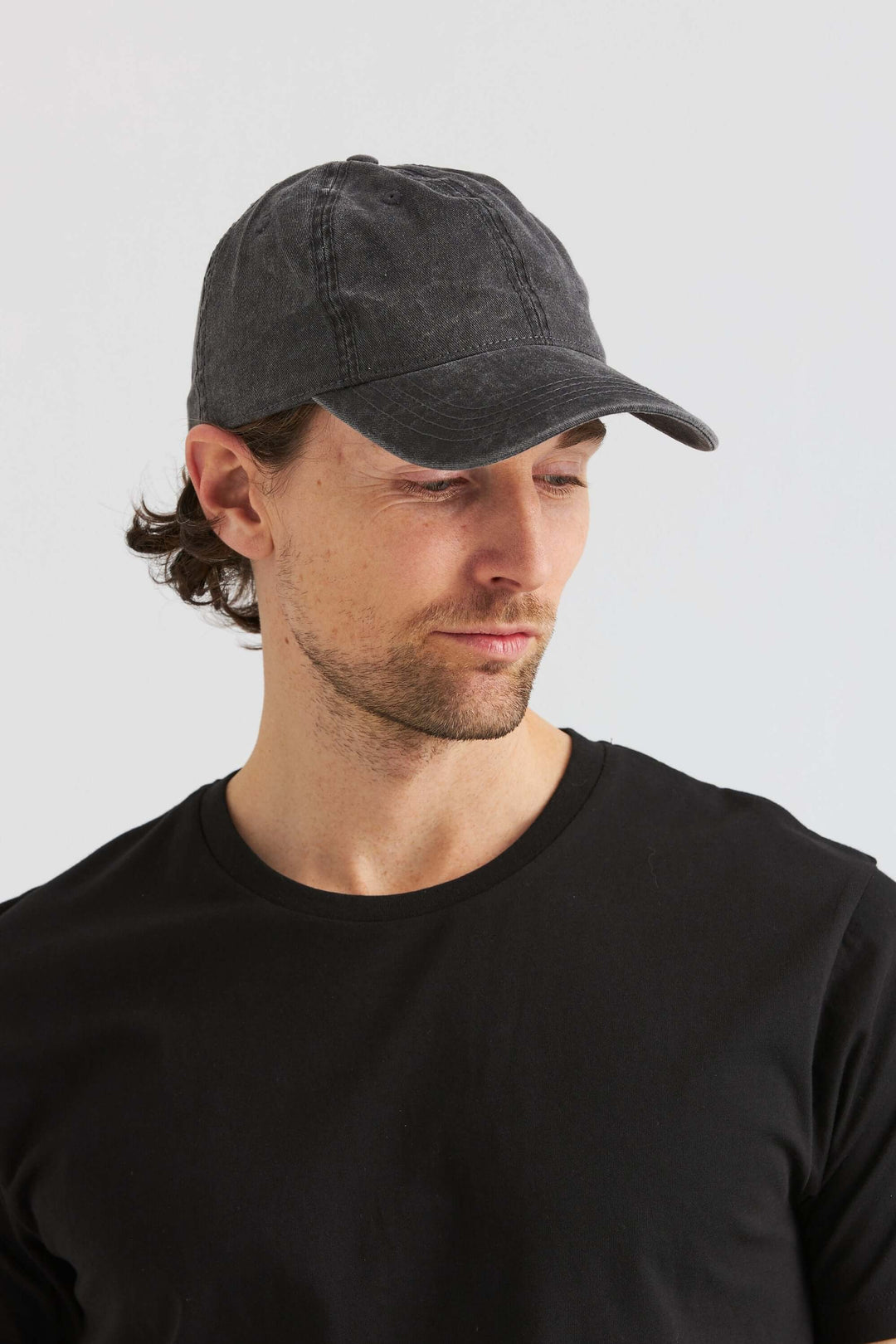 Svart Keps Washed Cotton på en man, som visar klassisk design och mjuk bomullsmaterial