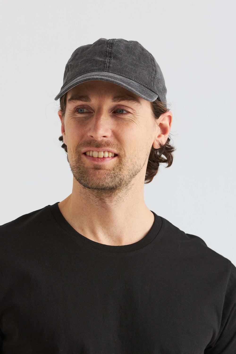 Svart Keps Washed Cotton på man i svart t-shirt, som visar en avslappnad stil med tvättad bomull.