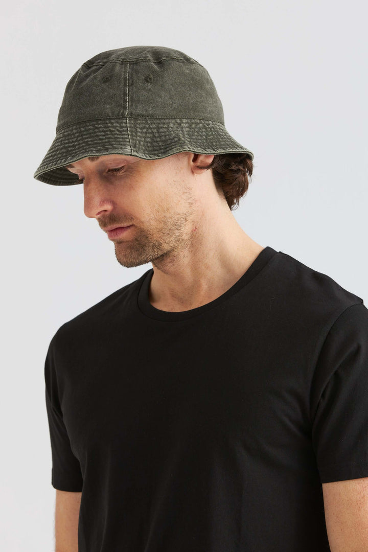 Grön Bucket Hat Washed Cotton som bärs av man i svart t-shirt, modern och avslappnad stil.