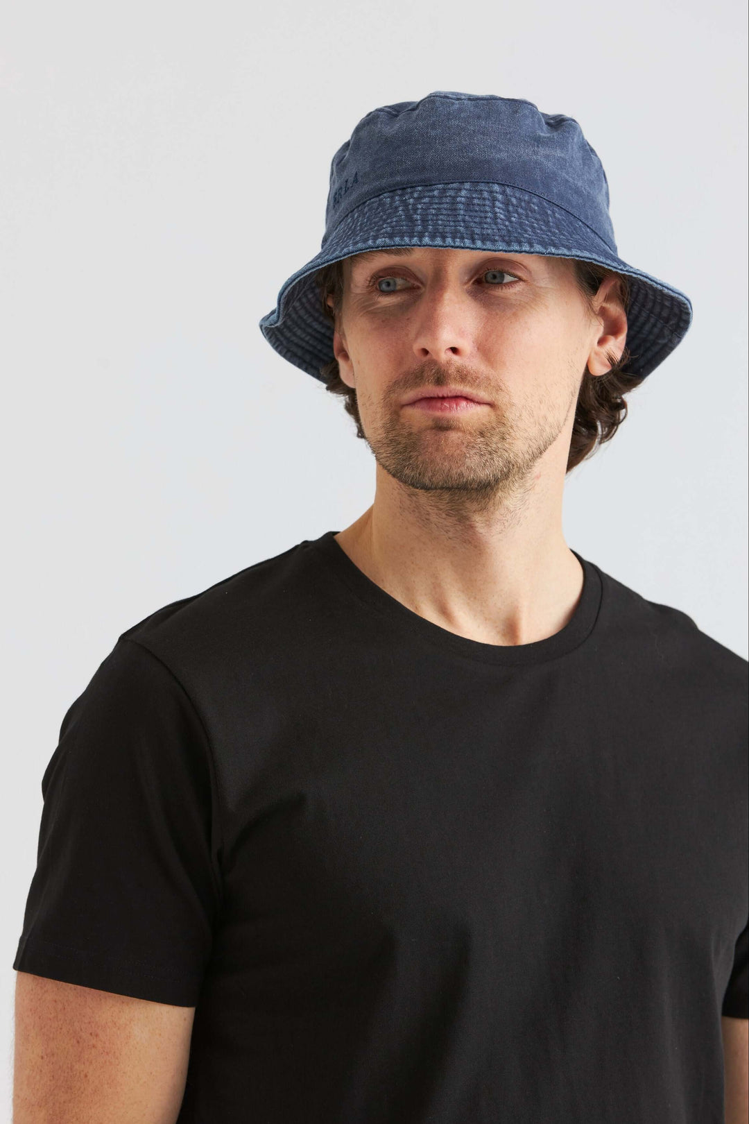 Man wearing a Blå Bucket Hat Washed Cotton with a black t-shirt against a neutral background.