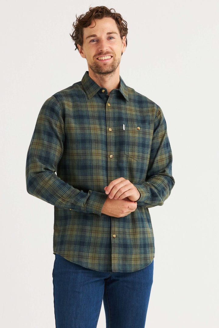 Man bär en flanellskjorta i skogsgrön med klassiskt rutmönster och jeans. Idealisk för hösten.