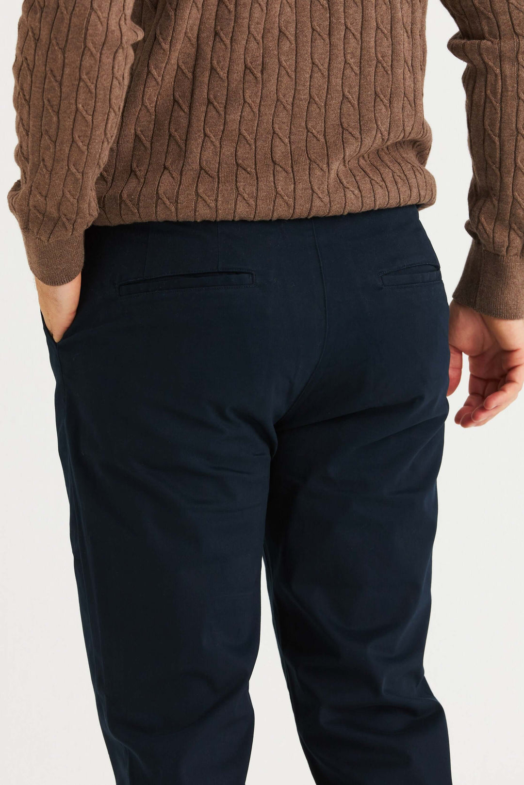 Marinblå Stretch Chinos sett bakifrån, bärs med en brun stickad tröja.