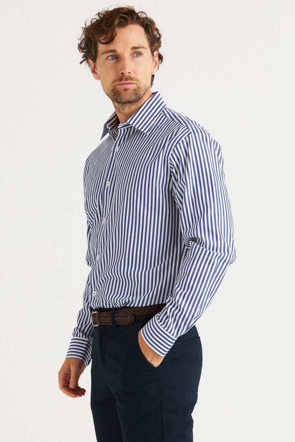 Man wearing a Blå Randig Skjorta featuring blue and white stripes, styled with dark trousers.