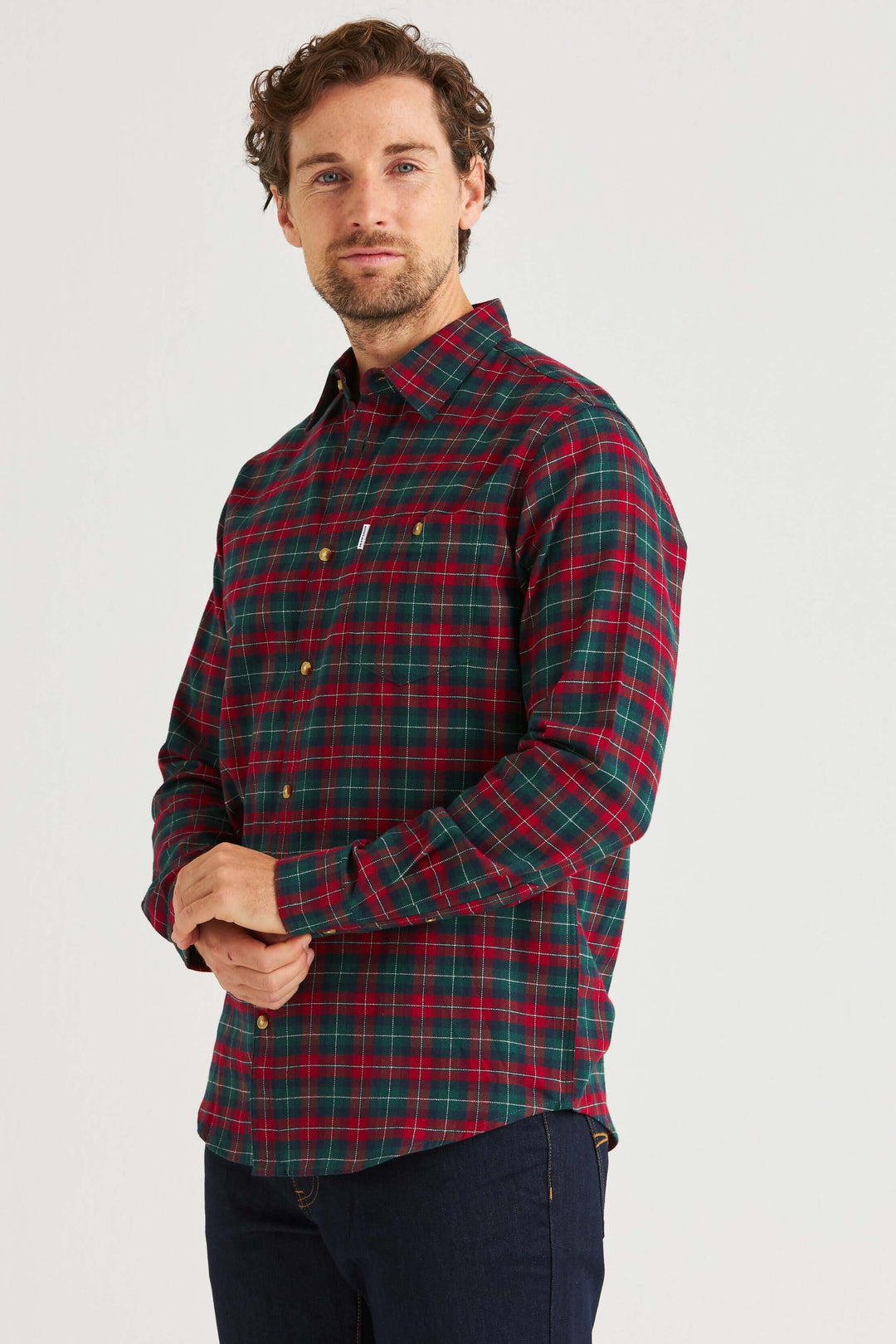 Man bär en flanellskjorta röd & grön med rutmönster, perfekt för en avslappnad vardagslook.