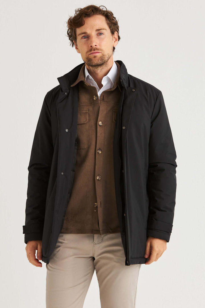Man iklädd Svart Cityjacka över bruna kläder, poserar skräddarsytt för en modern och stilren look.