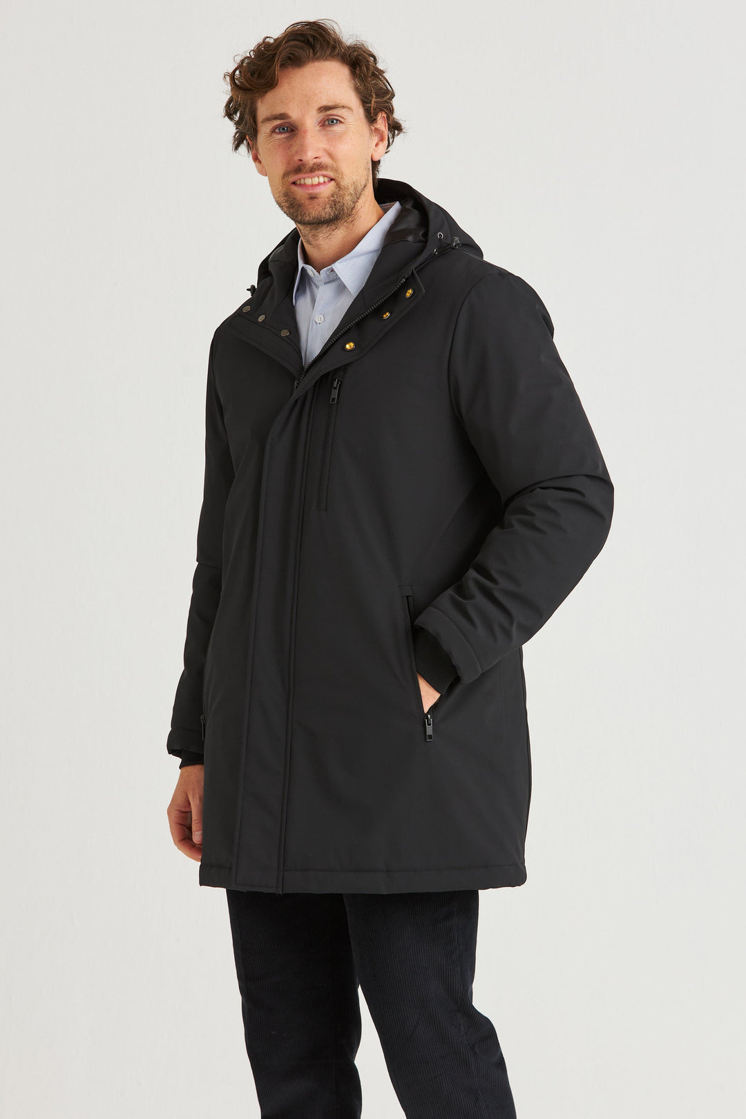 Svart Lång Cityjacka worn by a man, showcasing its stylish, comfortable design and hood for added warmth.