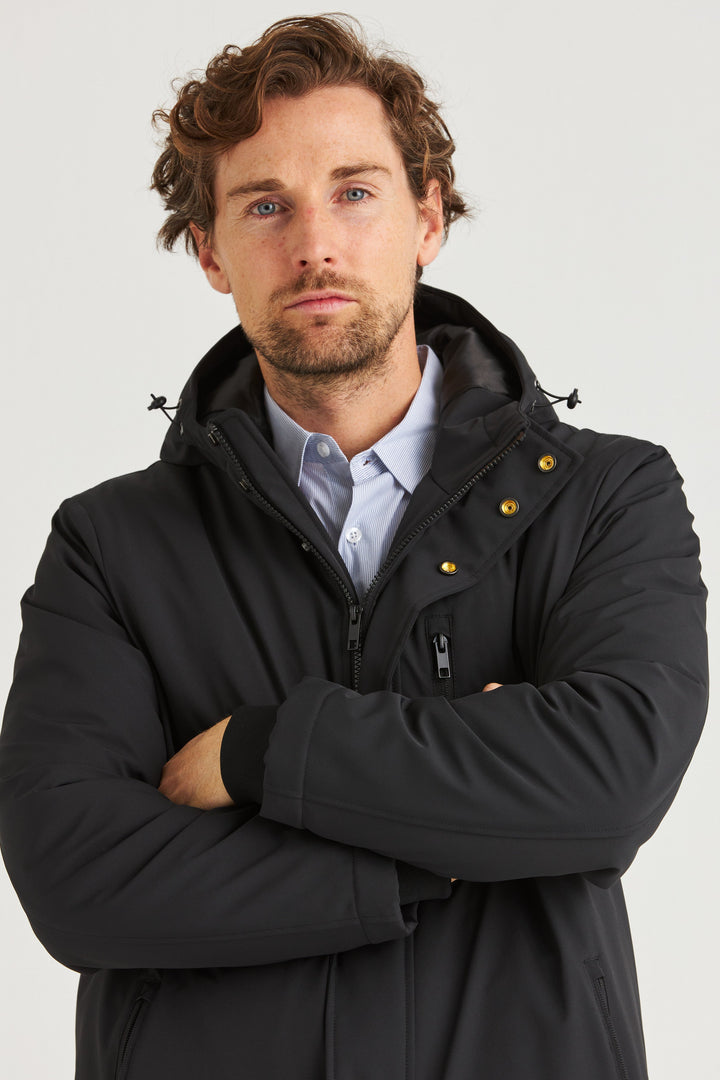 Svart Lång Cityjacka, en man i jacka med huva som visar dess bekväma och stilrena design.