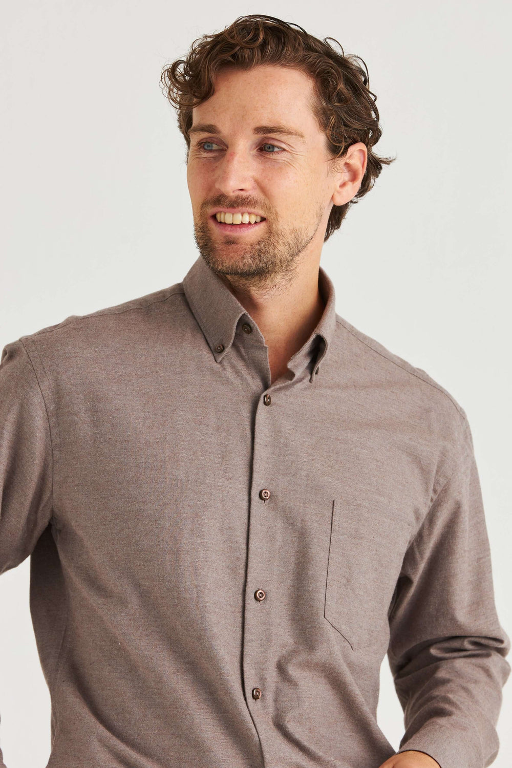 Beige Lyocellskjorta Button Down visad på man med lockigt hår. Skjortan har en button down-krage och mjuk textur.
