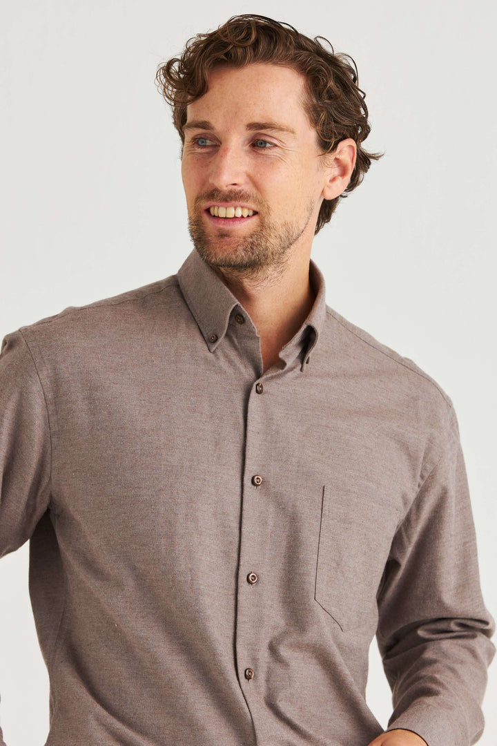 Beige Lyocellskjorta Button Down visad på man med lockigt hår. Skjortan har en button down-krage och mjuk textur.