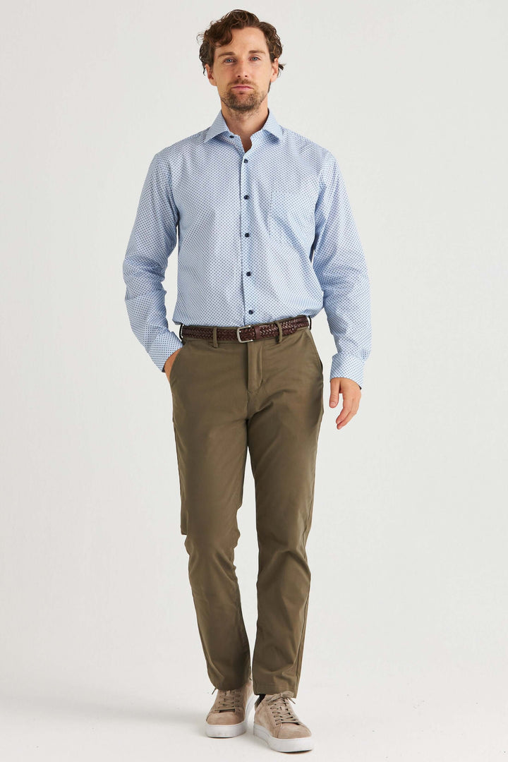 Man i ljusblå skjorta med småmönster och olivgröna byxor, stilren och modern outfit.