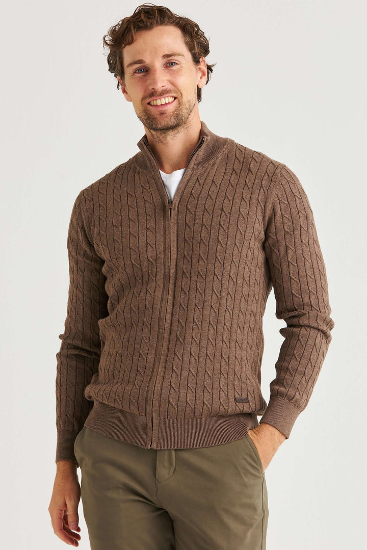 Man bär en Brun Kabelstickad Full Zip i 100% bomull med ett klassiskt flätmönster.