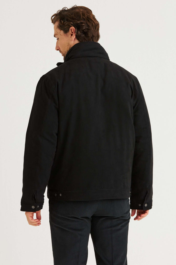 En man som bär en svart jacka, sett bakifrån, med ståkrage och stilren design.