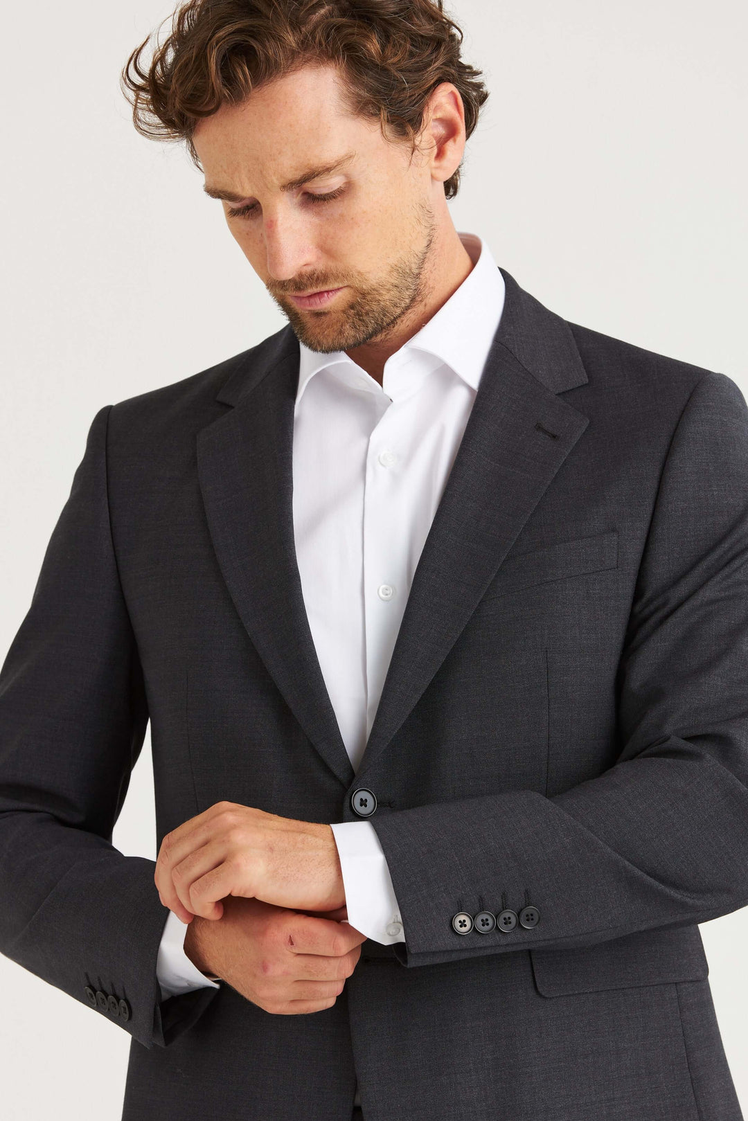 Man i Dexter Kavaj Grå som justerar sin skjorta, elegant och modern stil.