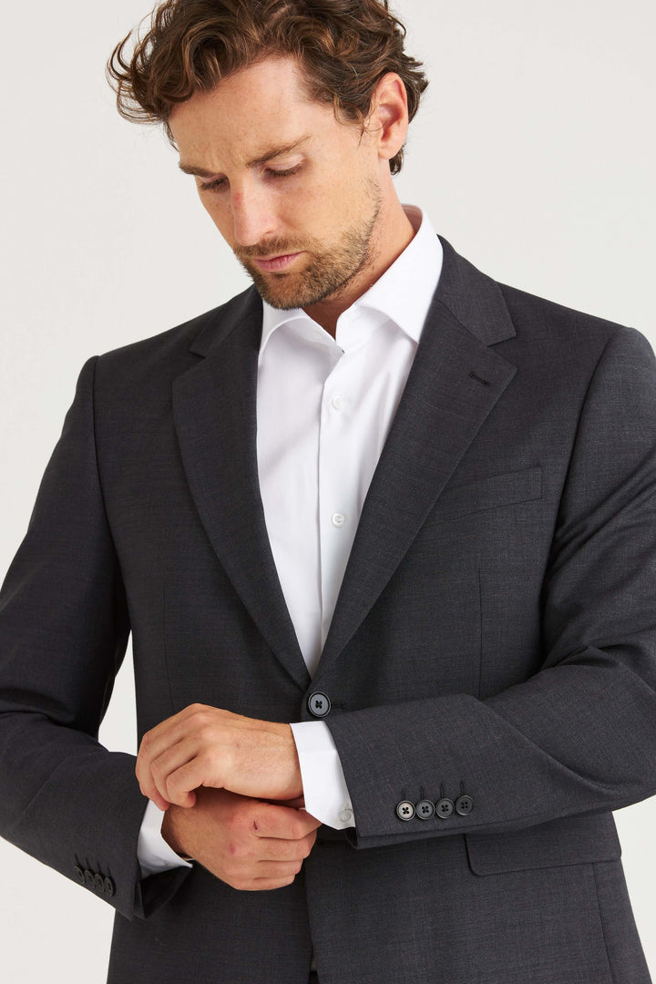 Man i Dexter Kavaj Grå som justerar sin skjorta, elegant och modern stil.