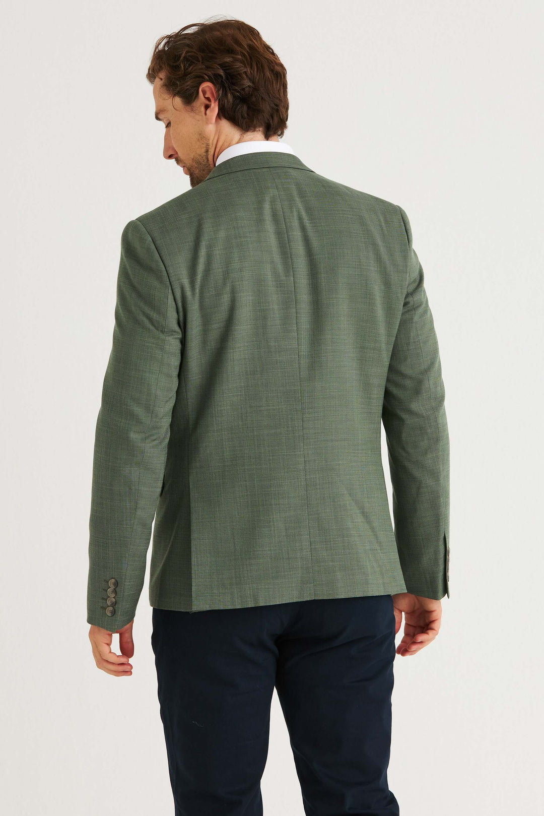Man wearing a Grön Kavaj from the back, showcasing its stylish and modern green fabric.