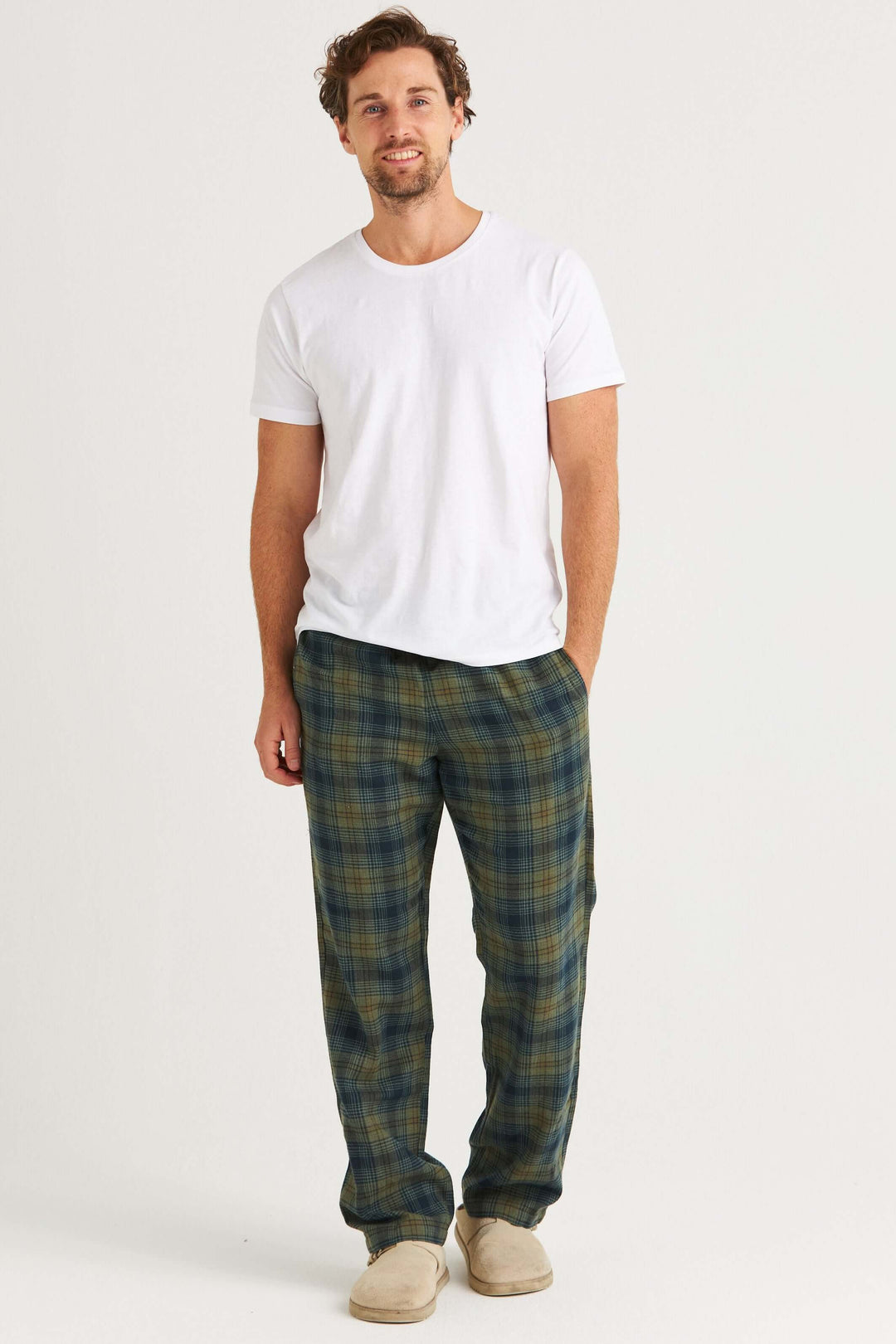 Man i vit t-shirt och grönrutig pyjamasbyxa i flanell, perfekt för avkoppling och hemmabruk.