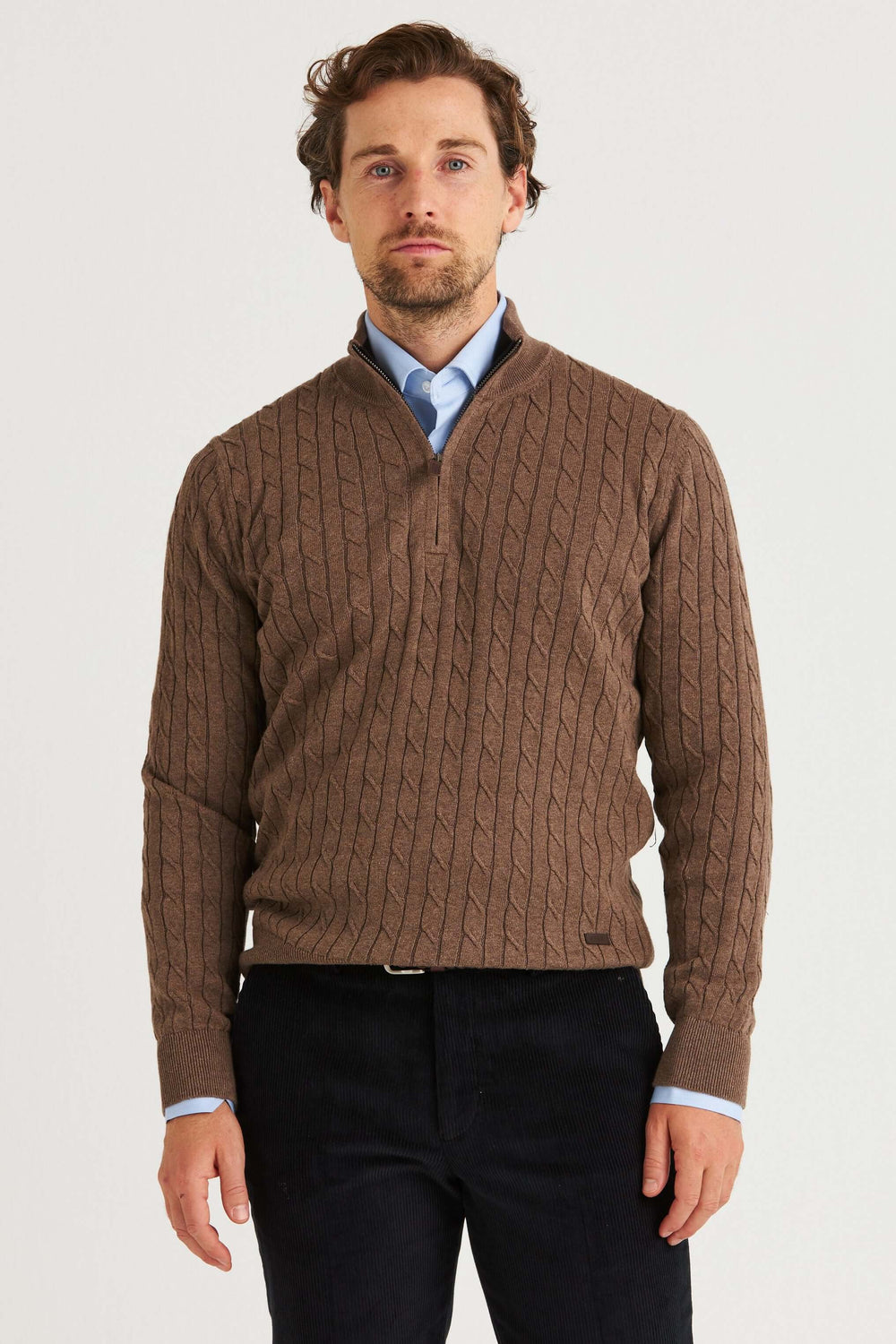 Brun Kabelstickad Half Zip en manlig modell i en varm brun tröja med kabelstickning och kort dragkedja.