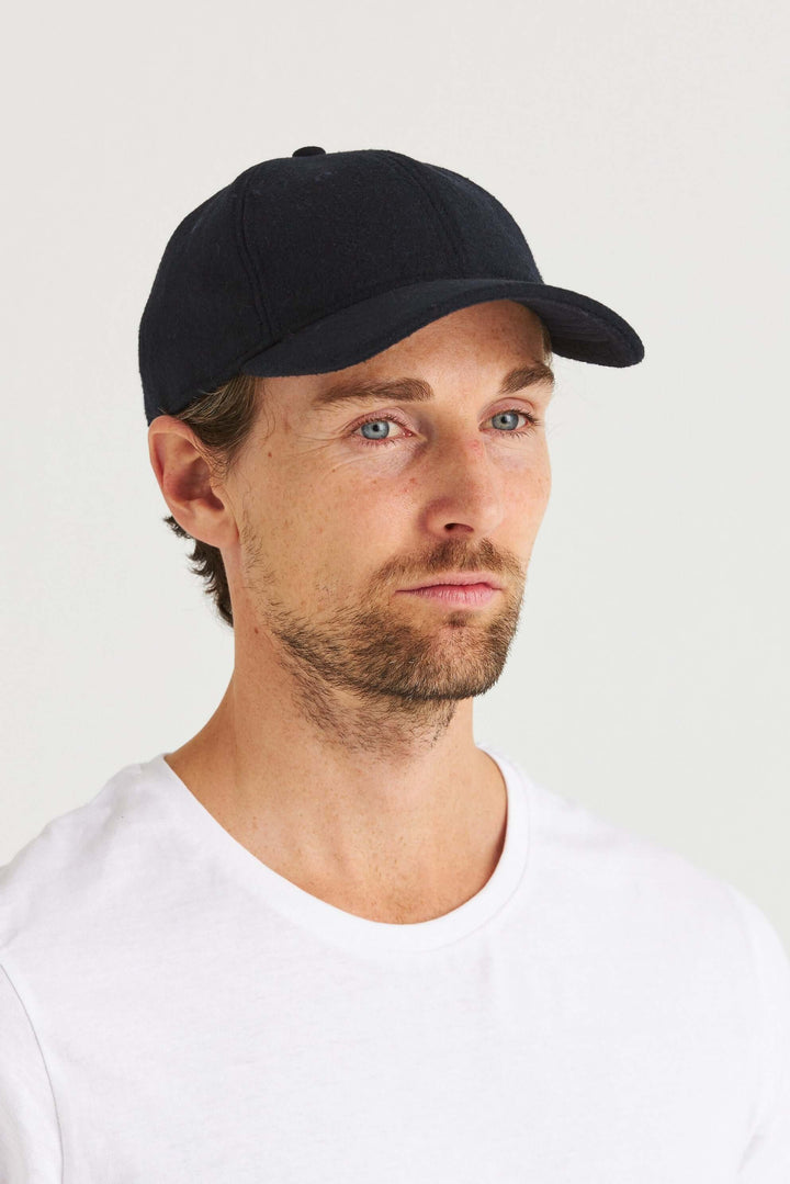 Marinblå Keps Wool Look på en man med ljus t-shirt, som visar kepsens stilrena design och mjuka kvalitet.
