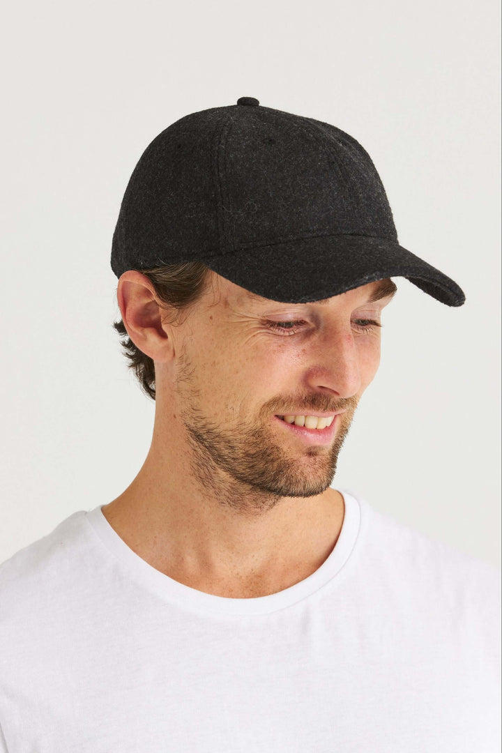 Grå Keps Wool Look på en man med lergrå t-shirt, lergrå ullinspirerad keps, leende ansikte.