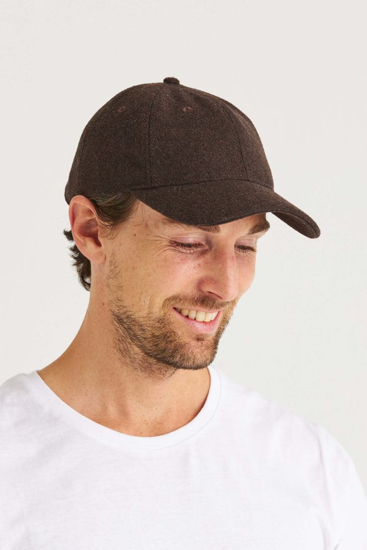 Brun Keps Wool Look på man som ler i en vit t-shirt, med en stilren och mjuk cap i ullinspirerad design.