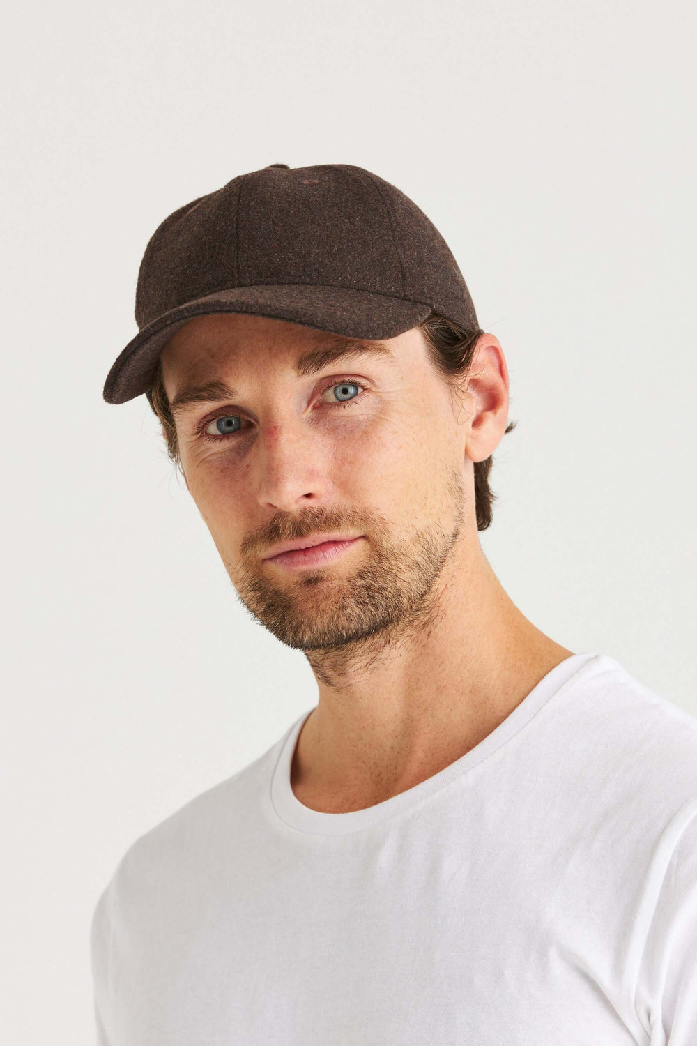 Brun Keps Wool Look, stilren brun keps med ullinspirerad look på en man i vit t-shirt.